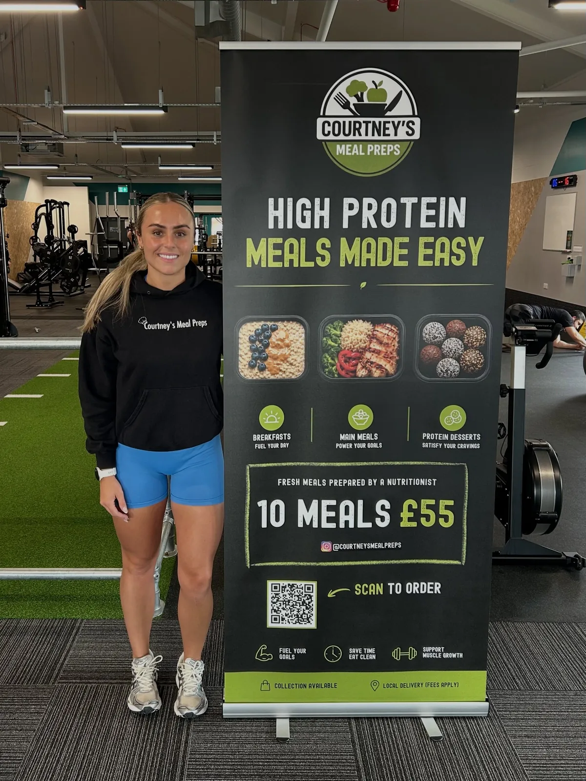Courtney standing beside the Courtney's Meal Preps banner at the gym